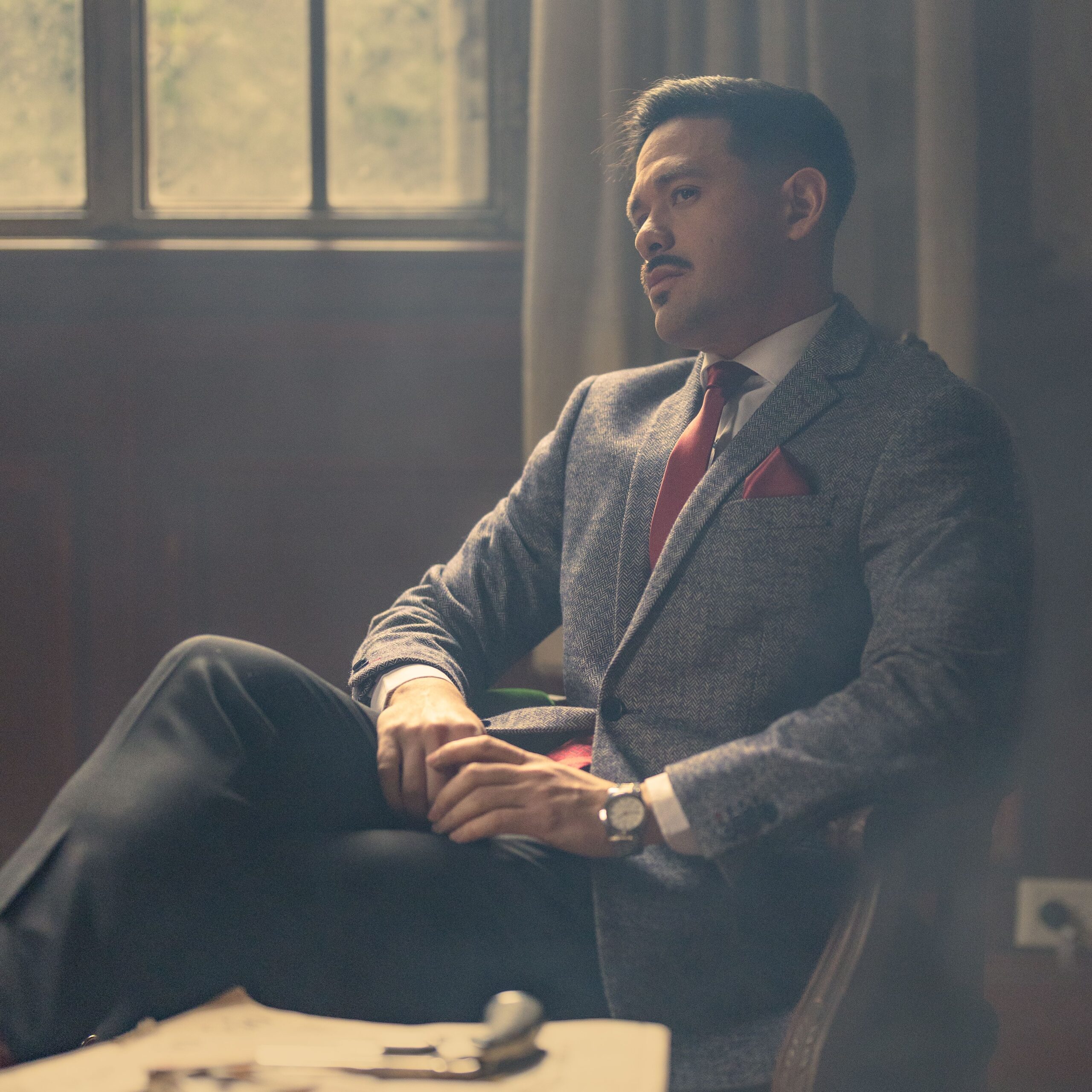 A sophisticated man in a suit relaxing in a vintage office, creating a mood of elegance.